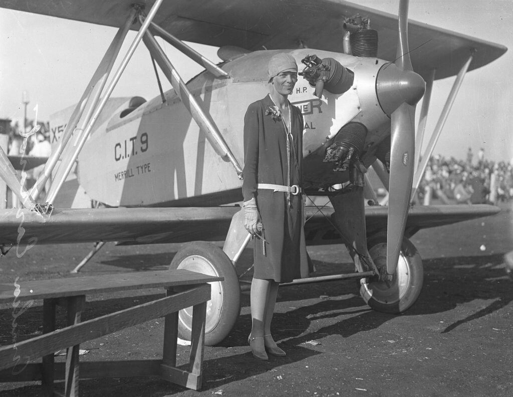 An image of Amelia Earhart standing in front of a plane, 10 years prior to her disappearance